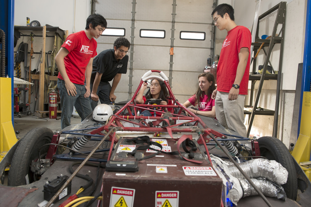 Five students working together on the frame of a solar electric vehicle.