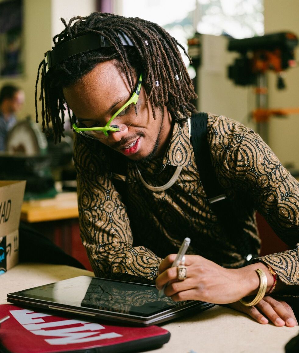 A student wearing an MIT Brass Rat ring uses a stylus and computer tablet.