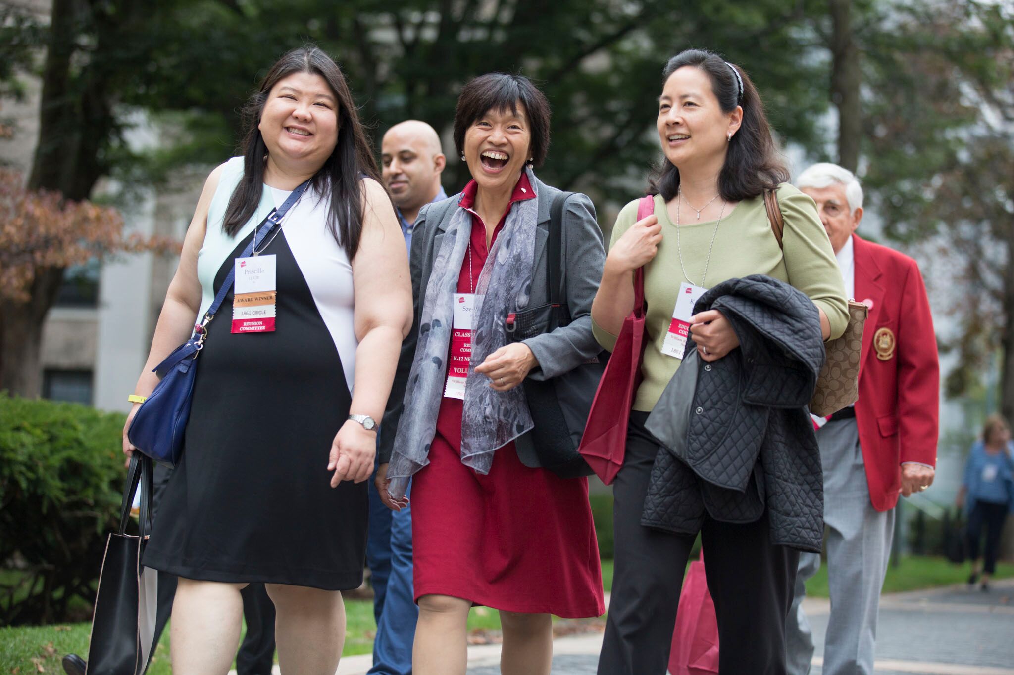 A group of alumnae walking outside on the MIT campus. They are wearing name tags around their necks.